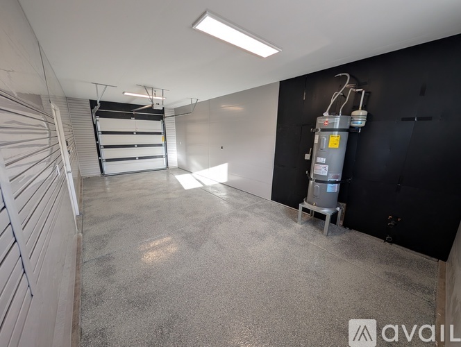 A spacious room with a grey floor and a black wall with a white door on the left side.
