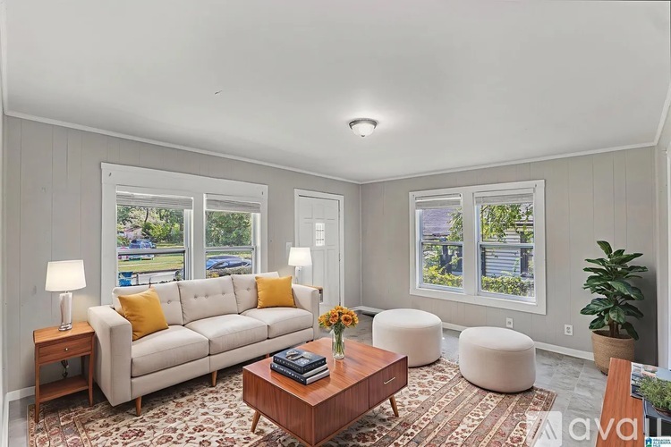A living room with a white couch, a coffee table, and a large window.