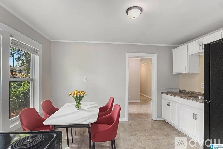 A kitchen with a table and chairs in the foreground and a refrigerator to the right.