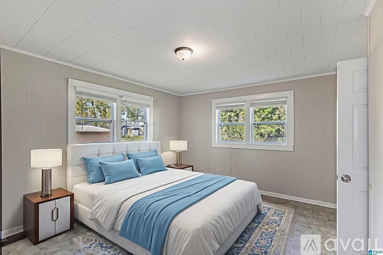 A bedroom with a bed, two lamps, and a window with a view of trees.