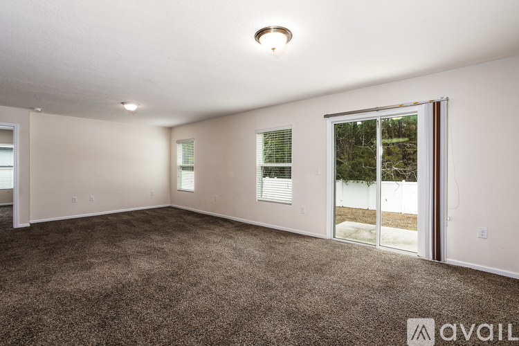 A spacious room with a carpeted floor and a large window.