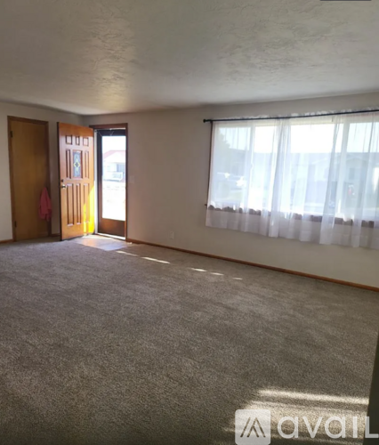A room with a carpeted floor and a window with curtains.