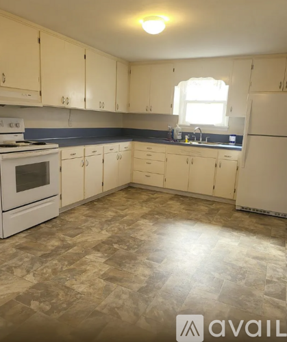 A kitchen with white cabinets and a tiled floor.