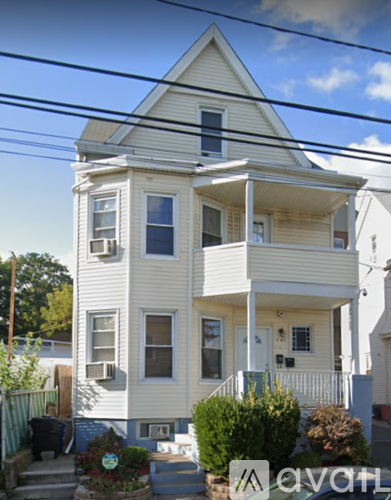 A two-story house with a white exterior and a balcony on the second floor.