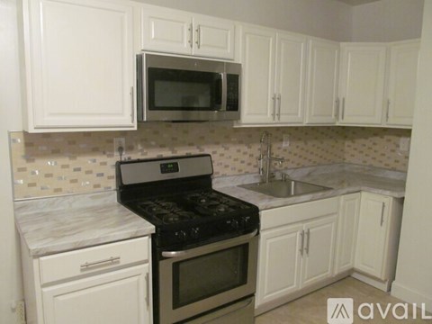 A kitchen with white cabinets and a black stove top.
