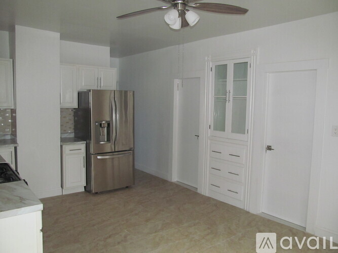 A kitchen with a refrigerator, cabinets, and a ceiling fan.