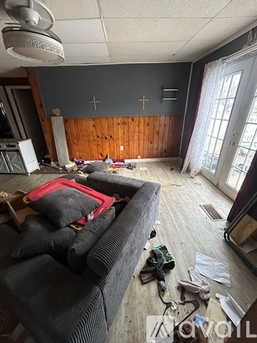A living room with a grey couch and a wooden wall.