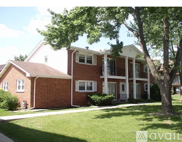 A red brick house with a tree in front.