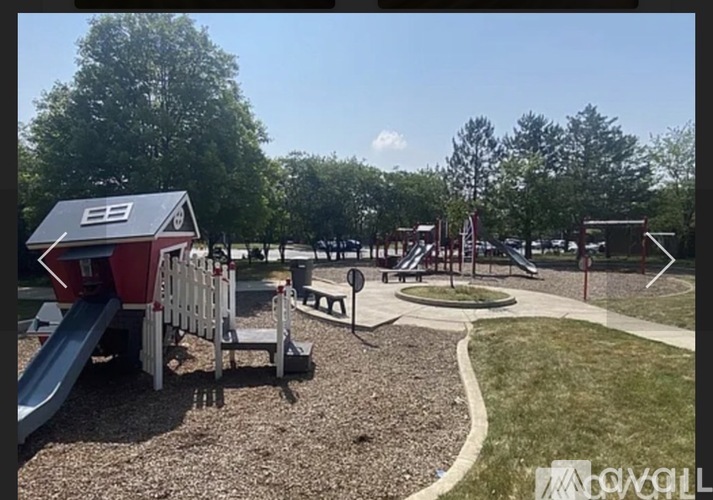 A playground with a red and white building, a slide, and a wooden fence.