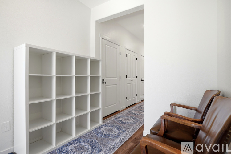 A room with a white shelving unit, a brown leather chair, and a blue patterned rug.