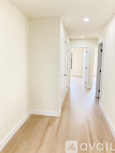 A long hallway with wood floors and white walls.