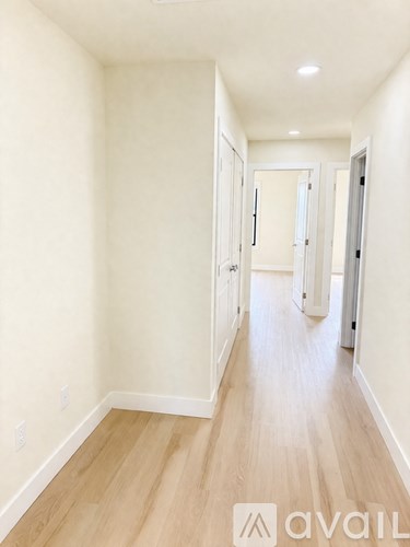 A long hallway with wood floors and white walls.