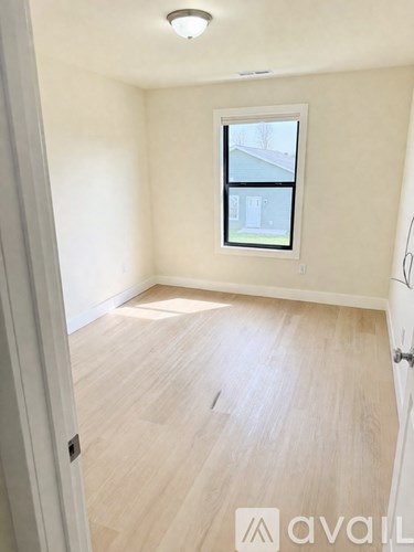 A room with a window and wooden flooring.