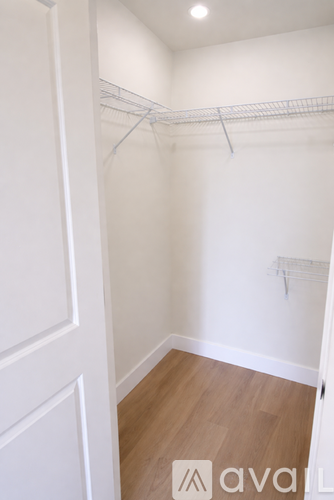 A white closet with a wooden floor and a white door.