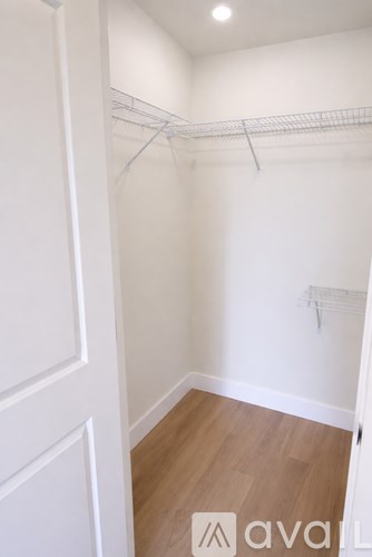 A white closet with a wooden floor and a white door.