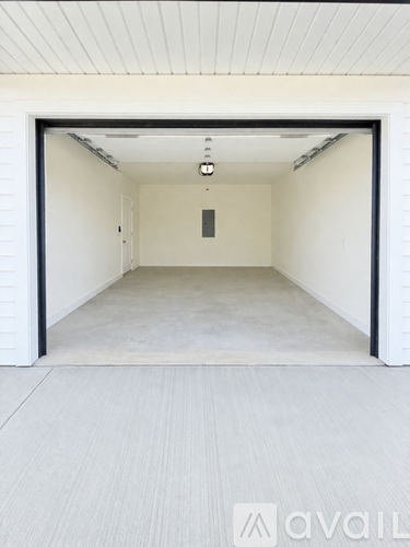 A white garage with a door open and a light on.