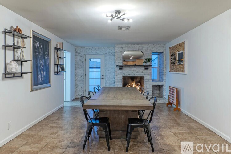 A dining room with a wooden table and chairs, a fireplace, and a painting on the wall.
