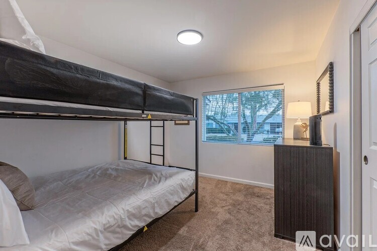 A bedroom with a bunk bed and a window with a view of trees outside.