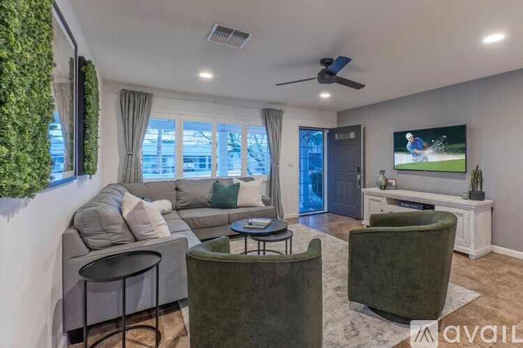 A living room with a grey sofa, a green armchair, and a television playing a golf game.