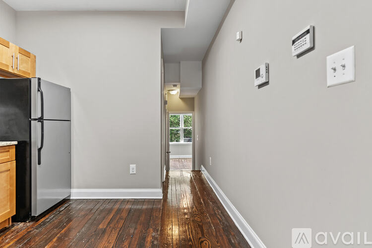 A kitchen with a black fridge and wooden floors.