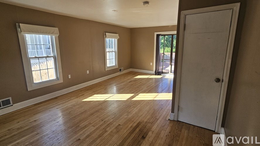 A room with wooden floors and a white door is available for rent.