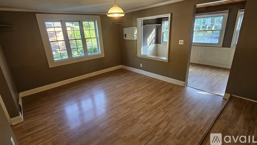 A room with wooden flooring and two windows.