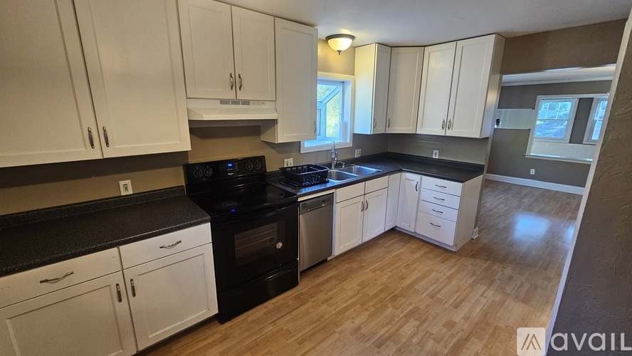 A kitchen with white cabinets and black countertops.