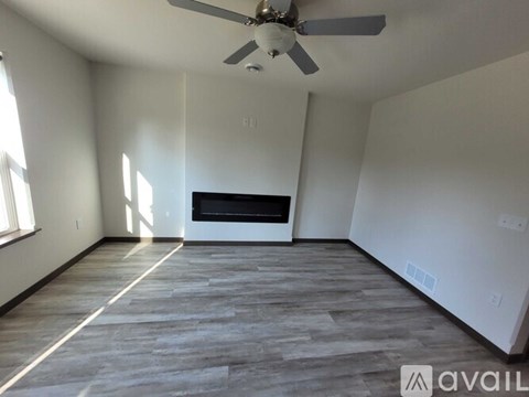 A spacious room with a ceiling fan and a fireplace.