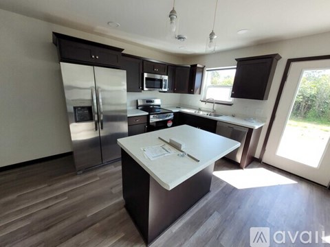 A modern kitchen with a refrigerator, microwave, oven, and sink.