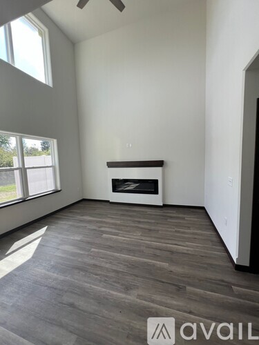 A spacious room with a fireplace and wooden flooring.