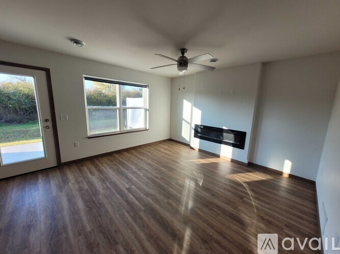 A spacious room with wooden flooring and a fireplace.