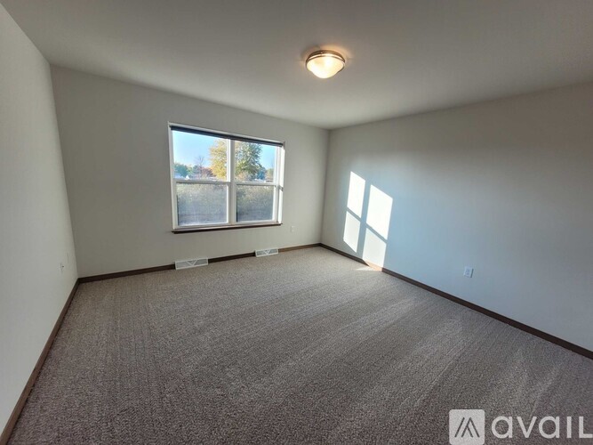 A room with a carpeted floor and a window showing trees outside.