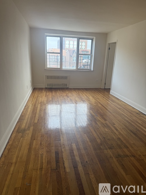 A room with wooden floors and a window showing a city view.