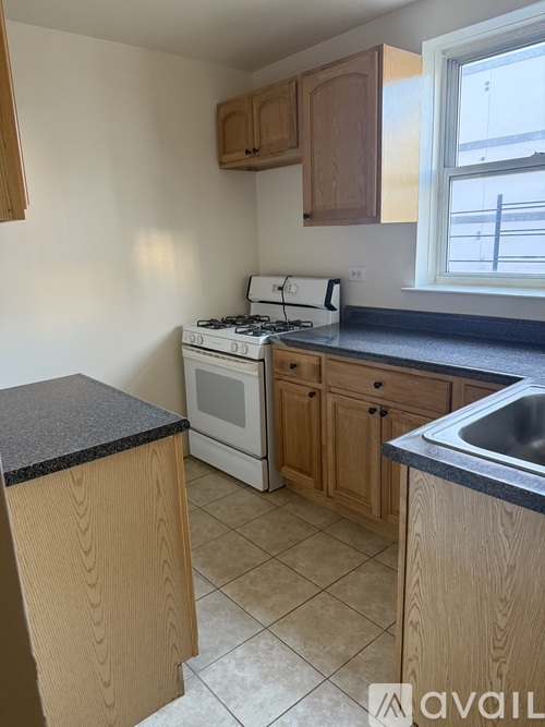A kitchen with a stove, sink, and cabinets.