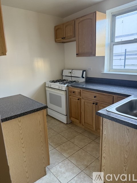 A kitchen with a stove, sink, and cabinets.
