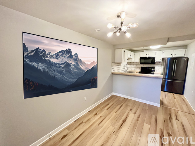 A large screen on the wall of a room with wooden flooring.