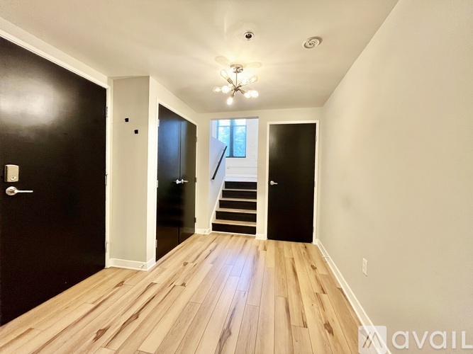 A hallway with wooden floors and a staircase leading to a second floor.