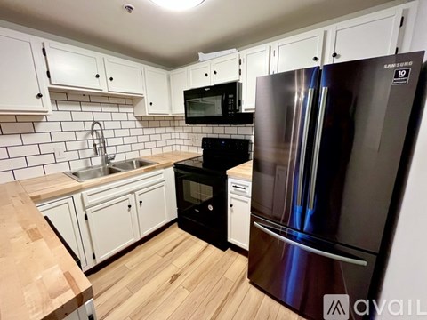 A kitchen with a black fridge and white cabinets.