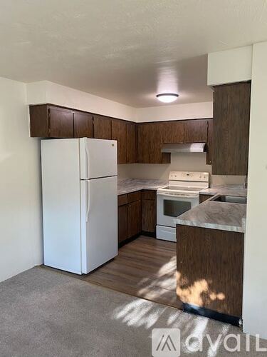 A kitchen with white appliances and wooden cabinets.