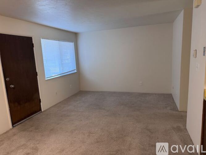 A room with a carpeted floor and a sliding glass door leading to a balcony.