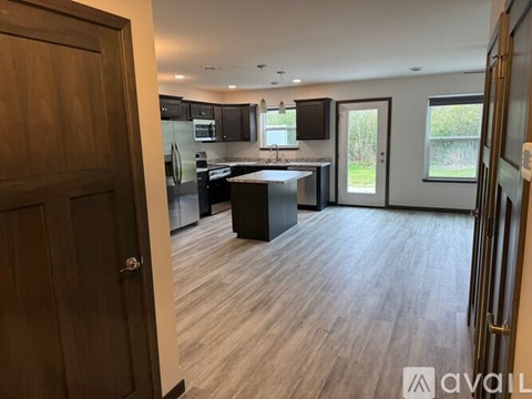 A kitchen with a wooden floor and a wooden door.