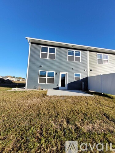 A grey house with a white door and windows on the side.