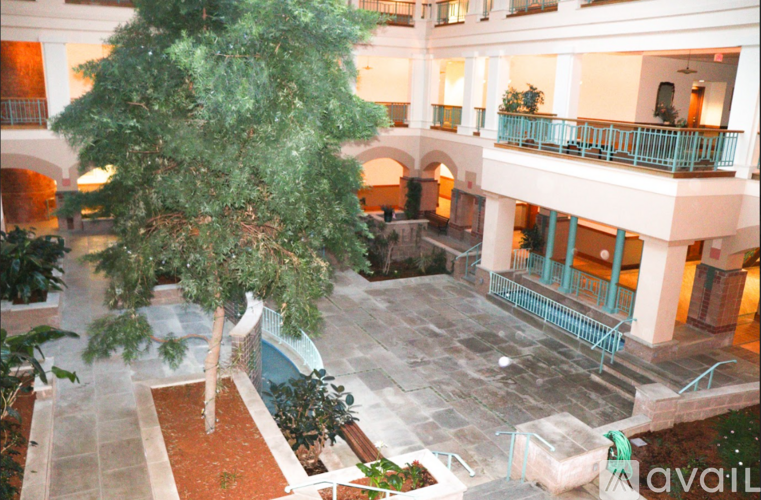 A courtyard with a tree in the middle and a balcony on the right.