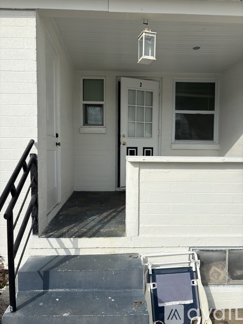 A white house with a black railing and steps leading to the front door.