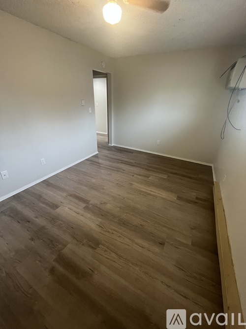 A room with wooden flooring and a door in the background.