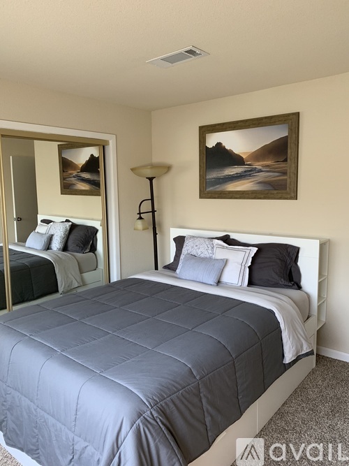 A bedroom with a large bed and a painting on the wall.
