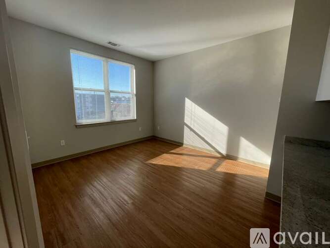A room with wooden flooring and a window letting in sunlight.