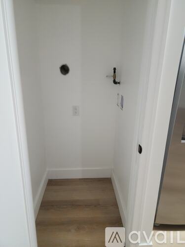 A white hallway with wood flooring and a mirror on the wall.