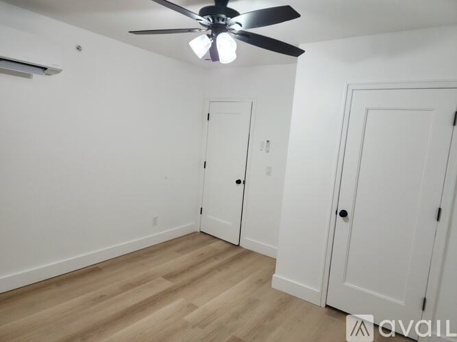 A room with a ceiling fan and three doors.