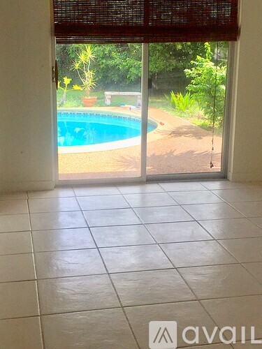 A tiled room with a view of a pool through a sliding glass door.